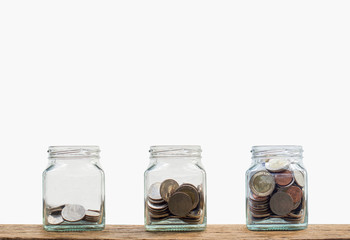 Investment concept. Growing coins three step in clear glass bottle on wooden table with white background. Conceptual saving money for growing business and future