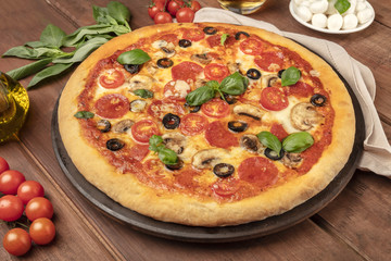 Pepperoni pizza on a pizza stone, with ingredients