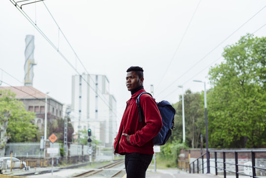 Portrait of young man waiting for train on railway platform