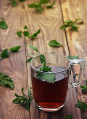 A fragrant herbal tea with mint leaves, lemon balm, raspberries and currants. Close-up. A cup of herbal tea on a wooden background.
