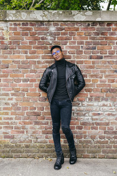 Black man posing on brick wall