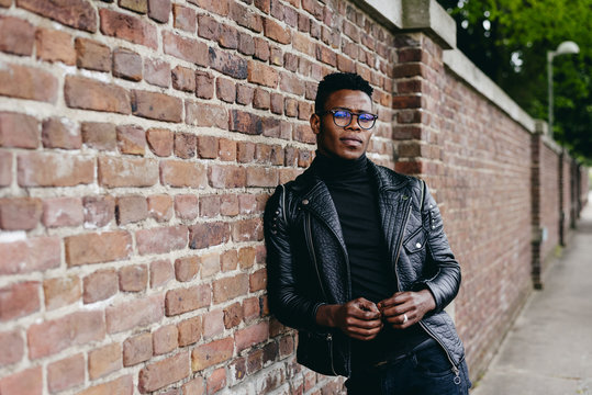 Black man posing on brick wall