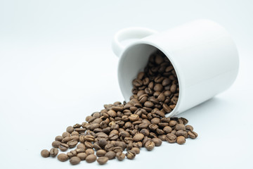 Food, Drink and Relaxation Concept. Close up of coffee bean with white mug cup of coffee on white background.