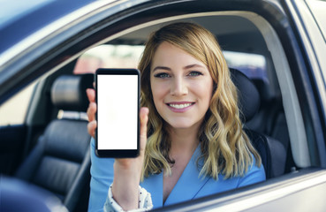 Young woman in auto shows smartphone with blank screen.
