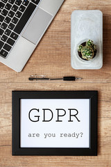Workspace with a laptop, cactus and a black frame with the word GDPR