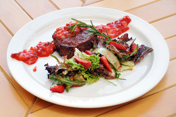 steak with strawberry sauce and vegetables on the table