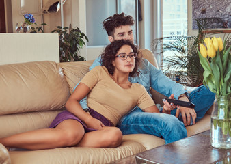 Young couple cuddling while watching TV at home.
