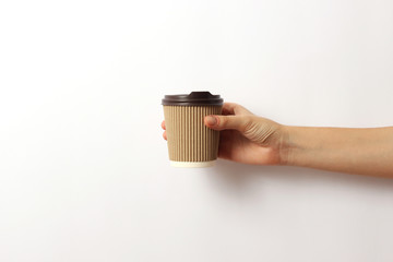 coffee in a cardboard glass in hand on a light background. minimalism, hot drinks.