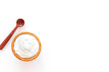 Healthy product, healthy meal. Greek yogurt in brown bowl near spoon on white background top view copy space