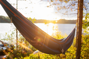 Relaxing in hammock outdoor near lake. View on sunset or sunrise. Nobody on photo