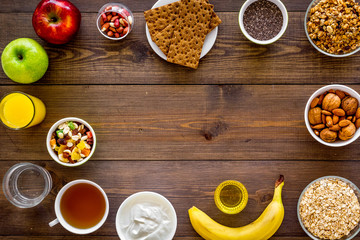 Set of products for healthy vegetarian breakfast. Fruits, oatmeal, yogurt, nuts, crispbreads, chia on dark wooden background top view space for text