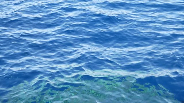 Blue transparent water surface on sea or ocean with small waves from the wind