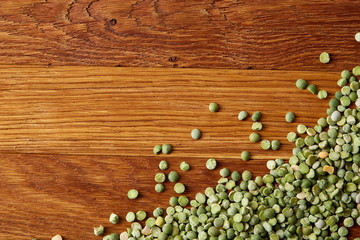 Green peas on rustic wooden background, close-up, top view, selective focus.