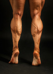 Detail on male bodybuilder calves muscles shot on black background.