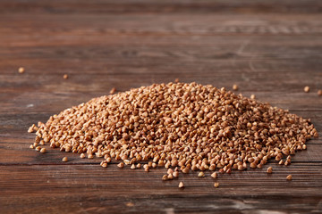 Obraz premium Pile of buckwheat groats on wooden background, top view, close-up, selective focus, shallow depth of field