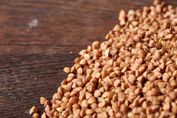 Buckwheat groats on wooden background, top view, close-up, selective focus, shallow depth of field
