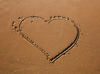 A drawing of a heart on a yellow sand.