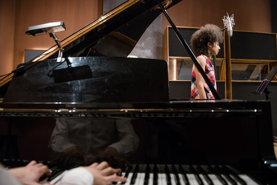 Crop man playing piano near vocalist