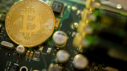 Bitcoin mining process - gold coin on computer circuit board with bitcoin processor and microchips. Electronic currency, internet finance rypto currency concept. Golden Bitcoin Cryptocurrency