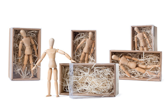 Wooden mannikin is standing near open cardboard box filled with wood shred while others are remaining inside. Concept of thinking outside the box, freedom, leadership.