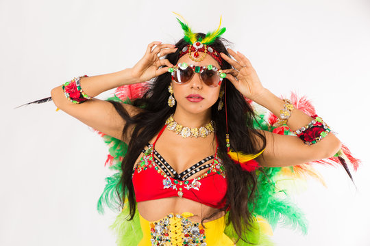 Very fit young hispanic woman in Carnaval costume and athletic shoes posing on clean white background