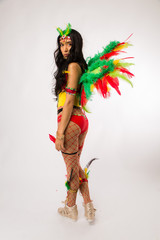 Skinny young dark haired hispanic woman in Carnaval costume and athletic shoes posing on clean...