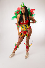 Fit young dark haired mixed race woman in Carnaval costume and athletic shoes posing on clean white...