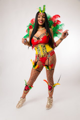 Fit young dark haired mixed race woman in Carnaval costume and athletic shoes posing on clean white background