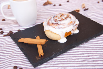 Homemade cinnamon roll and cinnamon sticks. Food background.