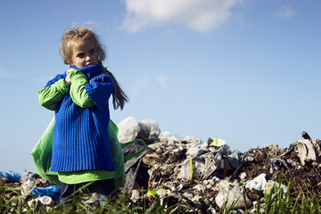 Poor hungry child with a heavy burden on his shoulders amid the garbage dump