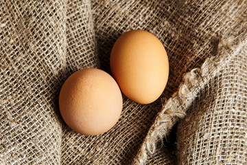 Two brown chicken eggs in on sackcloth texture