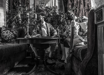 Actors in steam punk masks and antique costumes indoor. Black-white photo.