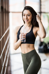 Fototapeta na wymiar Young slim fitness woman drink water after yoga exercises in yoga studio