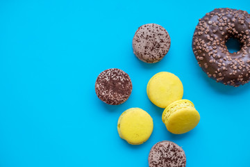 Colorful macarons cake, top view flat lay, sweet macaroon on candy blue background. Minimal concepts pattern above, food background. French sweet dessert and one donut .Copy space