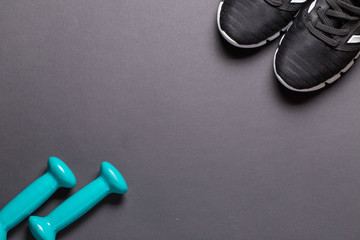 Black sneakers and turquoise dumbbells with a white sole on a black background