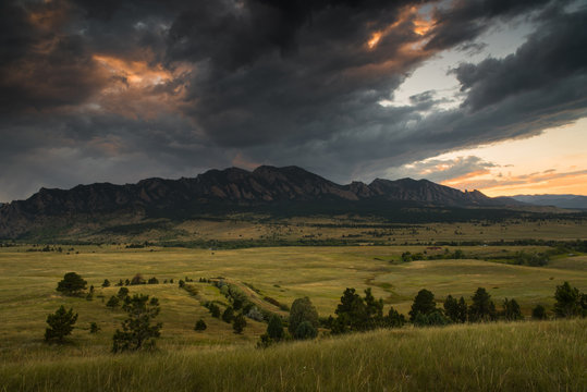 Dark clouds rolling over the Flatirons in Boulder, Colorado during sunset. 