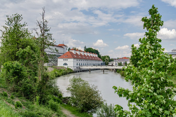 Fototapeta premium Old power station for energy generation on river bank with dam behind building