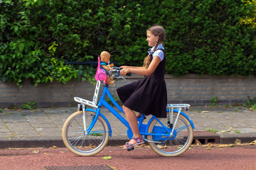 Girl in school uniform who rides bicycle. Back to school.