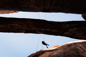 People rappelling off of Morning Glory Arch in Moab, Utah. 