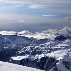 Winter mountains in clouds and ski slope