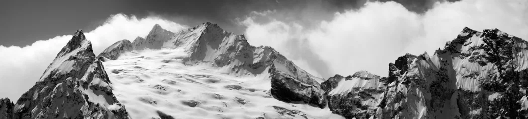 Schilderijen op glas Black and white panoramic view on snowy glacier and mountain peak © BSANI