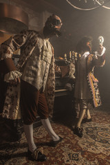 Actors in steam punk masks and antique costumes indoor.