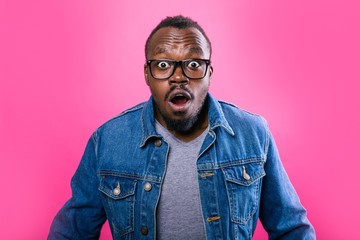 Fototapeta premium African man opened his mouth in surprise standing on a pink background