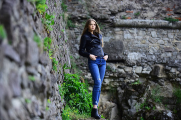 Naklejka na ściany i meble girl in casual clothes outdoor. look of girl near stony wall. Sexy woman with long hair at stone. Summer or spring fashion and beauty. sensual model with makeup after hairdresser.