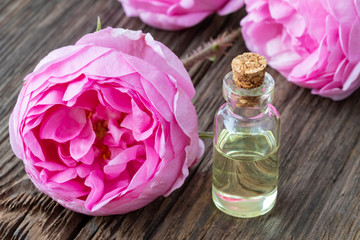 Obraz na płótnie Canvas A bottle of essential oil with roses on a wooden background