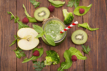 healthy green smoothie with banana, spinach, avocado and kiwi in a glass bottles on a rustic