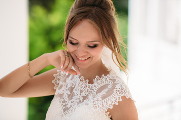 Portrait of the blonde bride, who is having fun and enjoying the wedding day. A girl in nature smiles and shows her beautiful eyes.