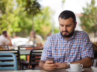 Handsome young man with phone in cafe.