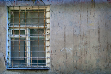 Fototapeta na wymiar Old window with an rusty grating on a old dirty wall.