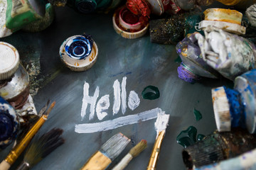 Bright oil paints in a tube on a dirty palette. Paints in use. Painting Hello.
